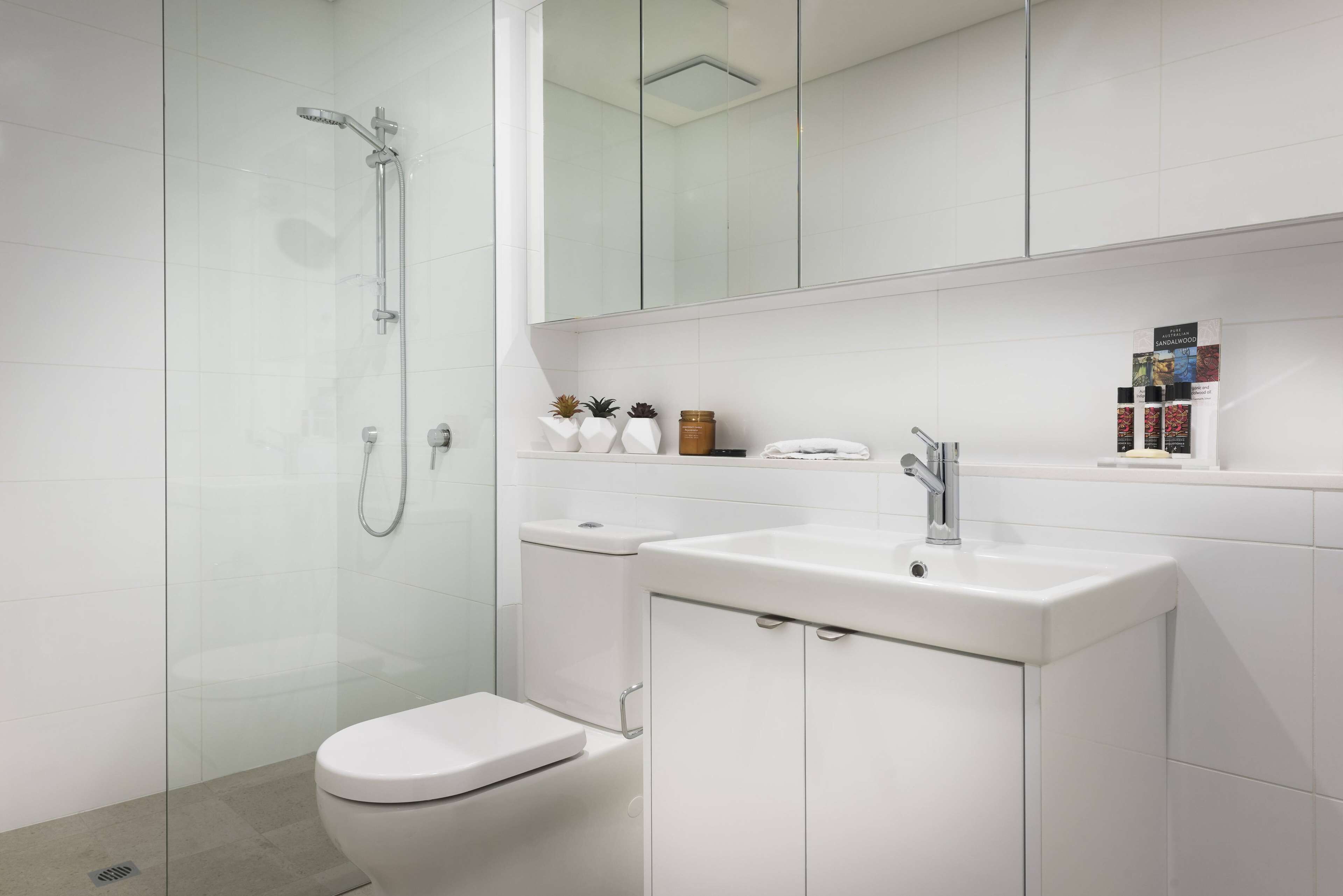 A modern bathroom with a glass-enclosed shower, a toilet, a sink, and a mirror above the sink.