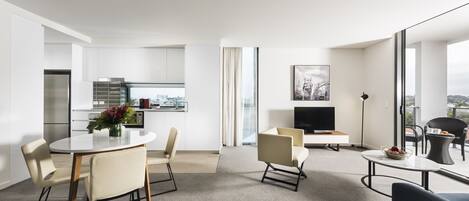 A modern hotel room with a dining area, a living area, and a kitchen.