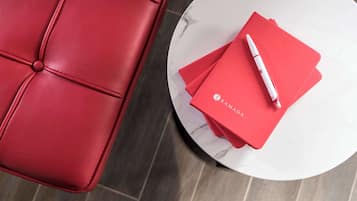 Un sofá de cuero rojo y una mesa de mármol blanco con carpetas rojas y un bolígrafo.