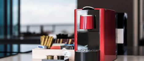 Una máquina de espresso roja y negra sobre una encimera con vistas a una ventana.