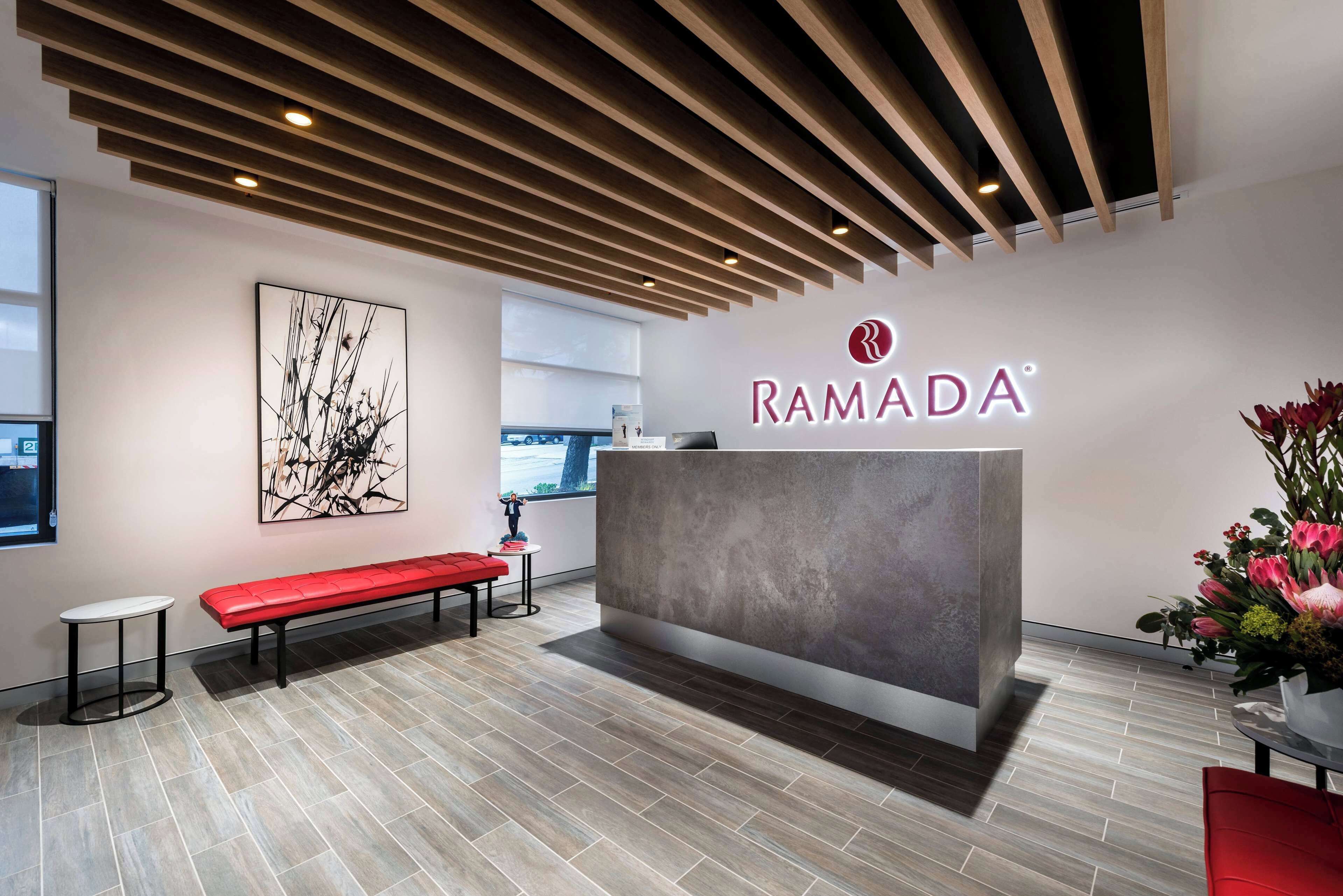Un área de recepción de diseño moderno, con mostrador de recepción, un banco rojo y una obra de arte en la pared.