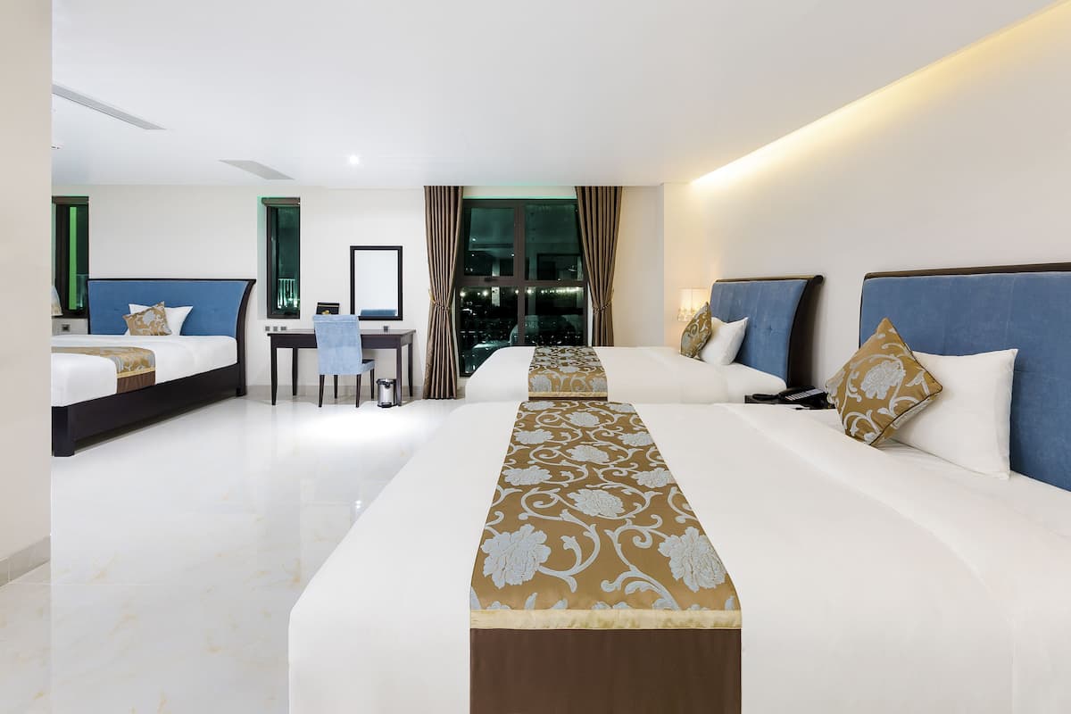 Ein Hotelzimmer mit zwei Betten, einem Schreibtisch und Blick auf die Stadt.