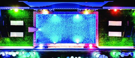 A stage with a "Royal Luxury Hotel" sign, surrounded by colorful lights and a patterned backdrop.
