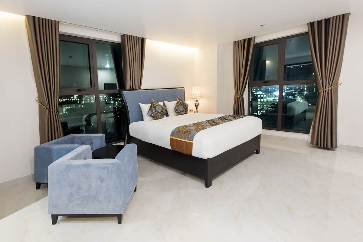 Ein modernes Hotelzimmer mit einem großen Bett, einer Sitzecke und Blick auf die Stadt.