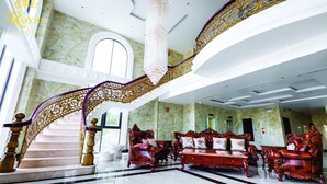 Eine prachtvolle Lobby mit einer Marmortreppe, aufwendigen Möbeln und einem Chandelier.