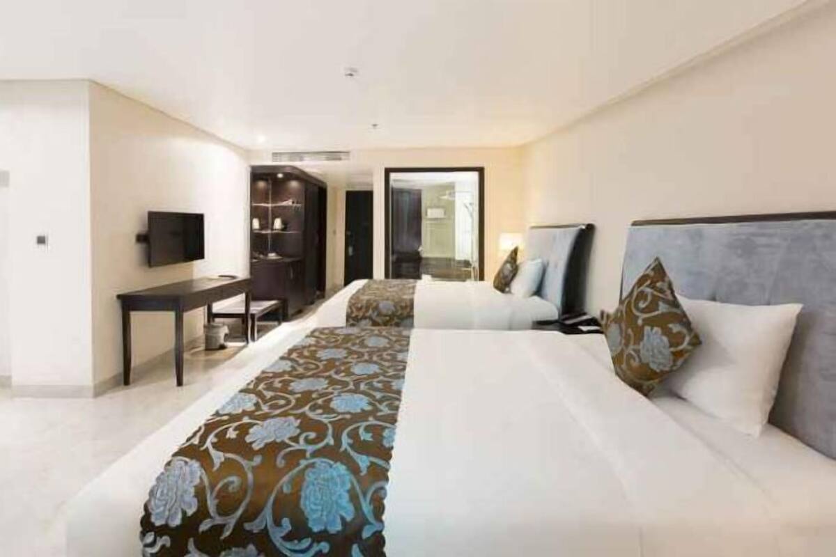 Ein Hotelzimmer mit zwei Betten, einem Schreibtisch, einem Fernseher und einem Kleiderschrank.