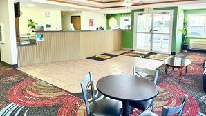 A reception area with a counter, a ceiling fan, a green wall, and a door marked 'EXIT'. - Super 8 by Wyndham Sweet Springs (Sweet Springs)