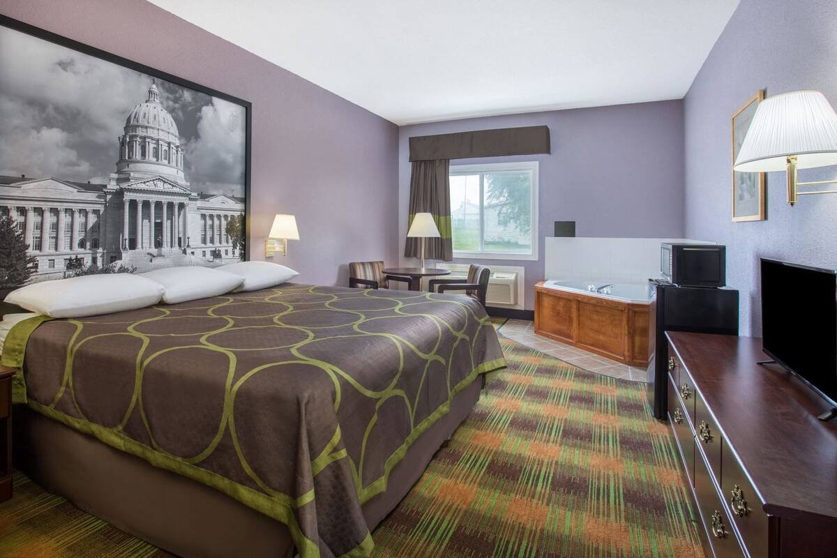 Una habitación de hotel con una cama grande, un escritorio, un televisor y un baño.