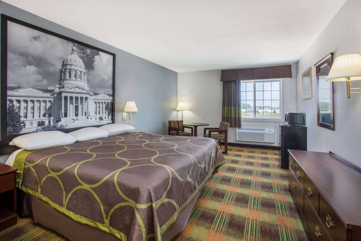 Una habitación de hotel con una cama grande, un escritorio, una silla, un televisor y una ventana con vistas.
