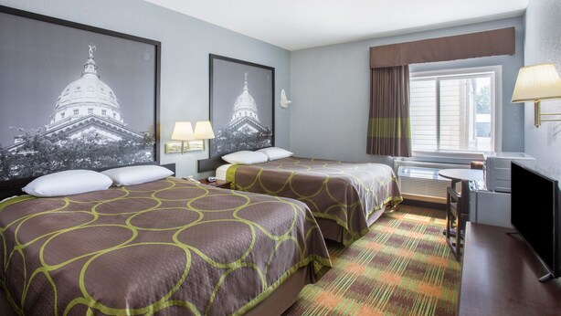 A hotel room with two beds, a desk, a chair, a TV, and two wall-mounted lamps. - Super 8 by Wyndham Sweet Springs (Sweet Springs)