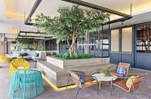 A modern outdoor seating area with a tree, a small table, and chairs. - Rooms Inc Semarang (Semarang)