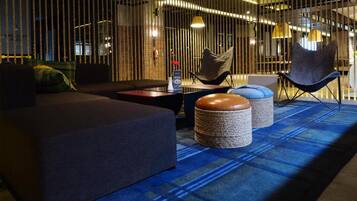 Un área de estar moderna con un sofá, sillones y otomanas.