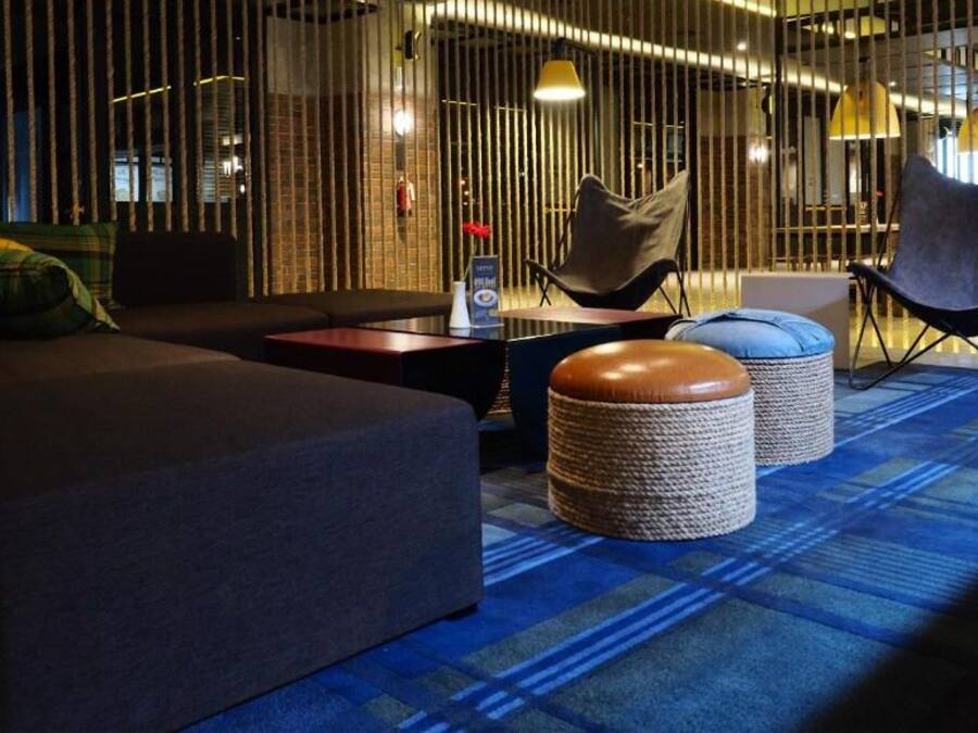 Un área de estar moderna con un sofá, sillones y otomanas.