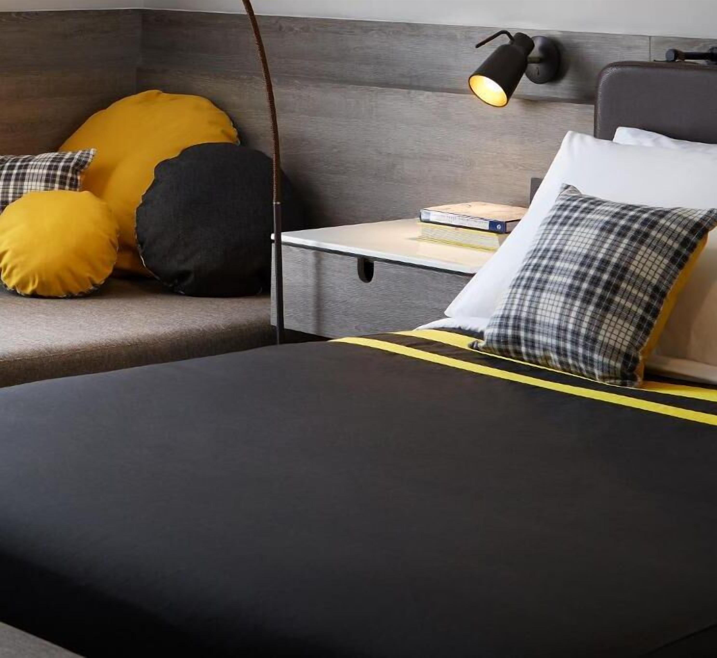 A modern bedroom with a bed, bedside table, and a lamp.
