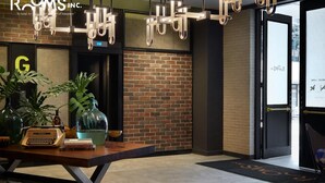 A modern hotel lobby with exposed brick walls, a reception desk with a vintage typewriter, and a large potted plant. - Rooms Inc Semarang (Semarang)