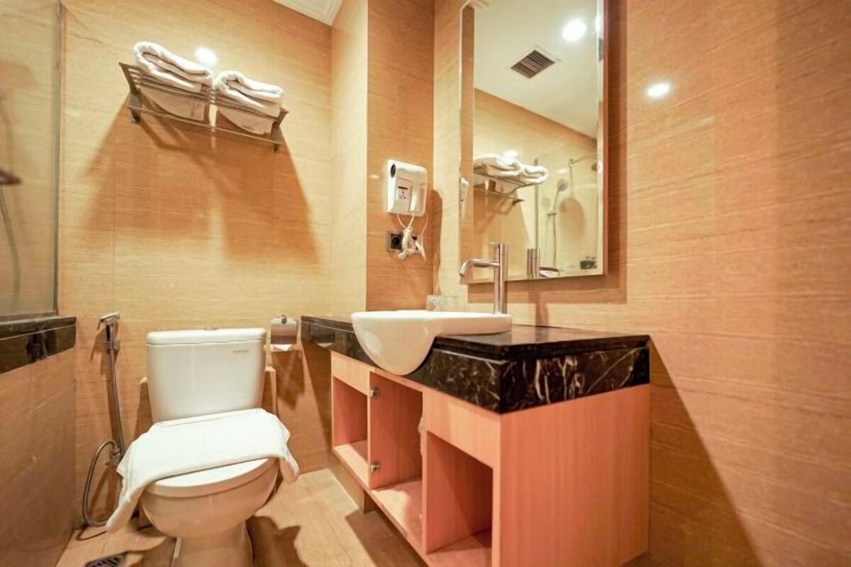 A bathroom with a toilet, sink, and mirror.