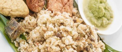 A plate of food with rice, fish, and a side of green sauce.
