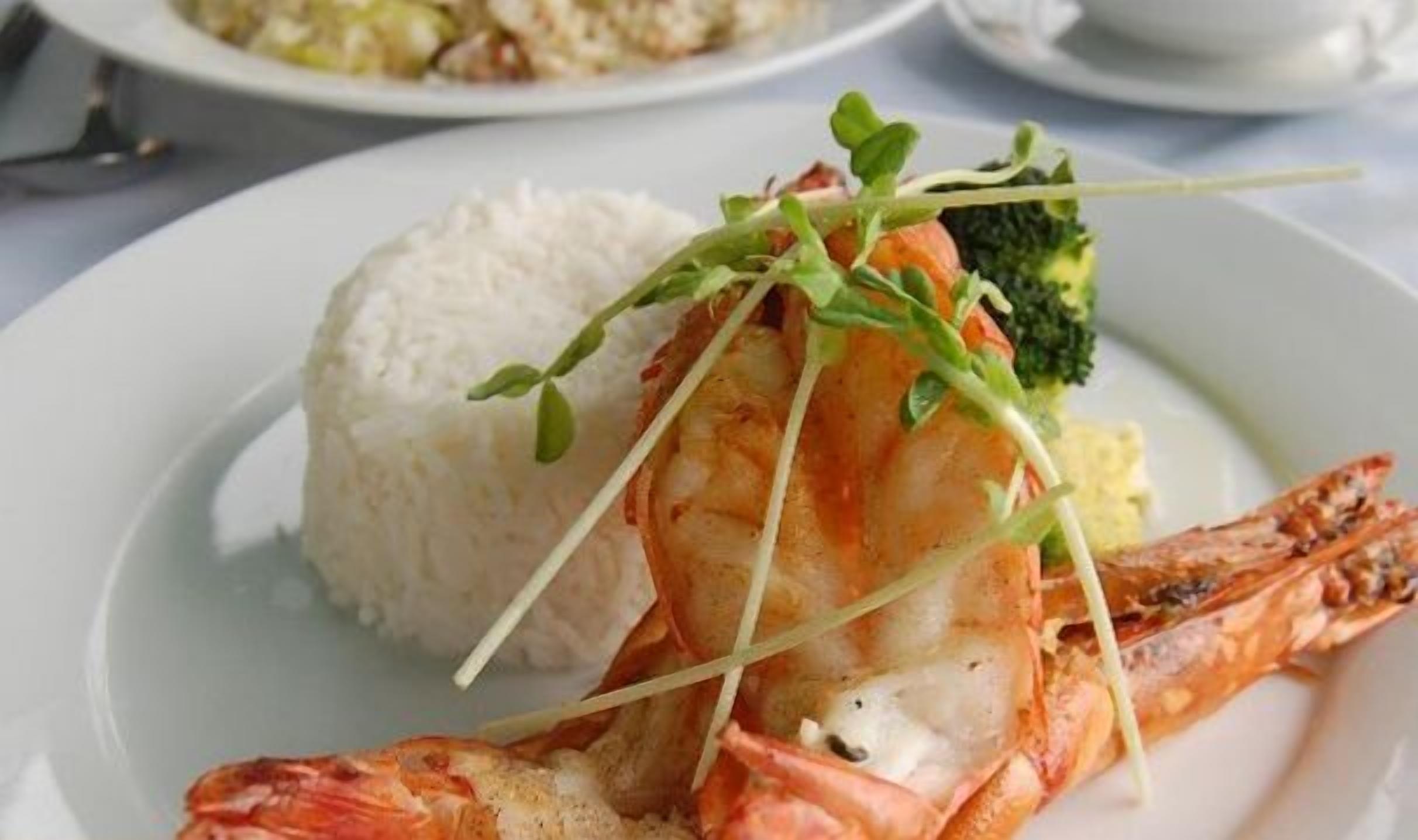 Un plato con un plato de camarones, arroz y brócoli.