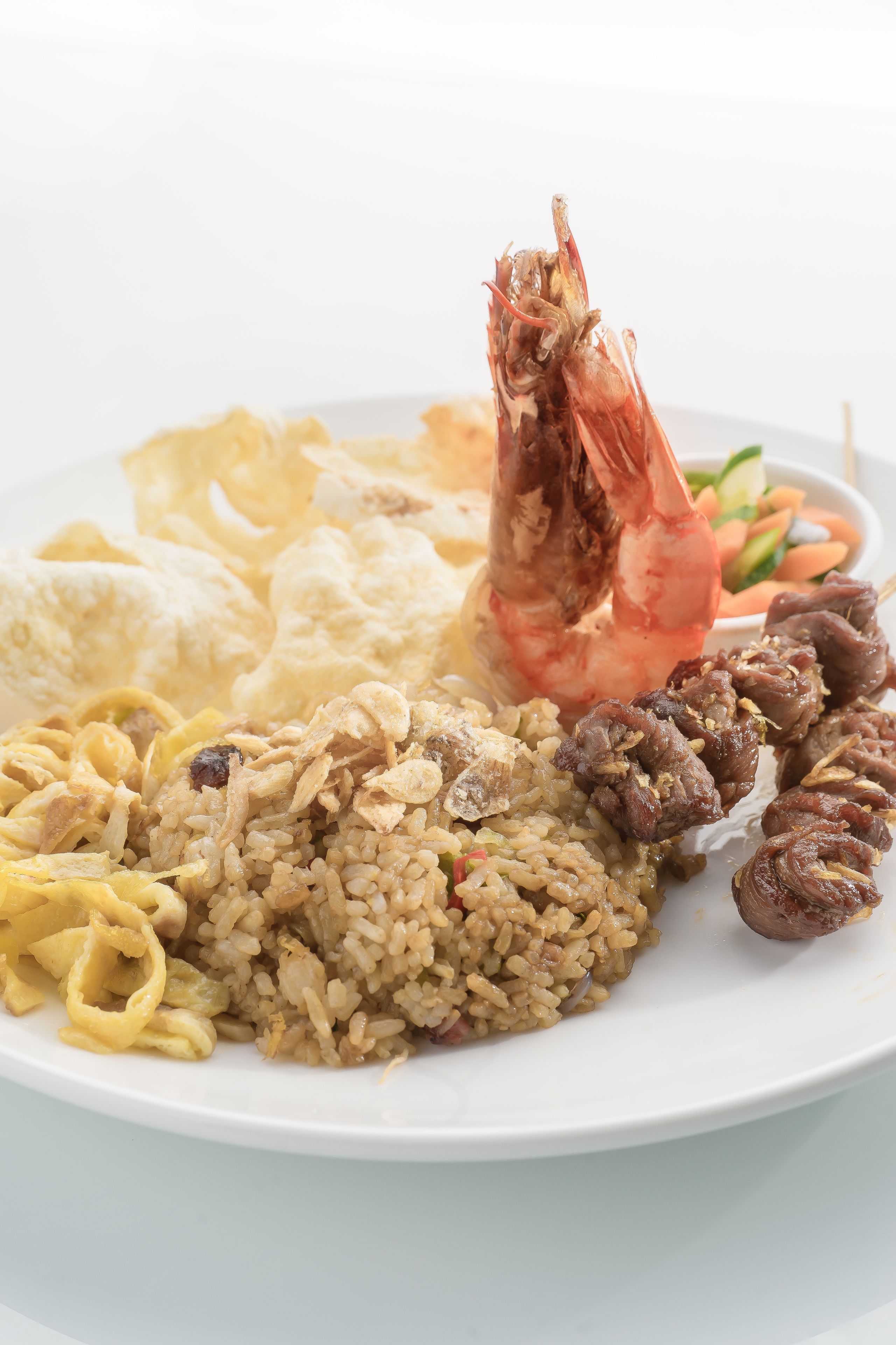 Un plato de comida con arroz, camarones y verduras.