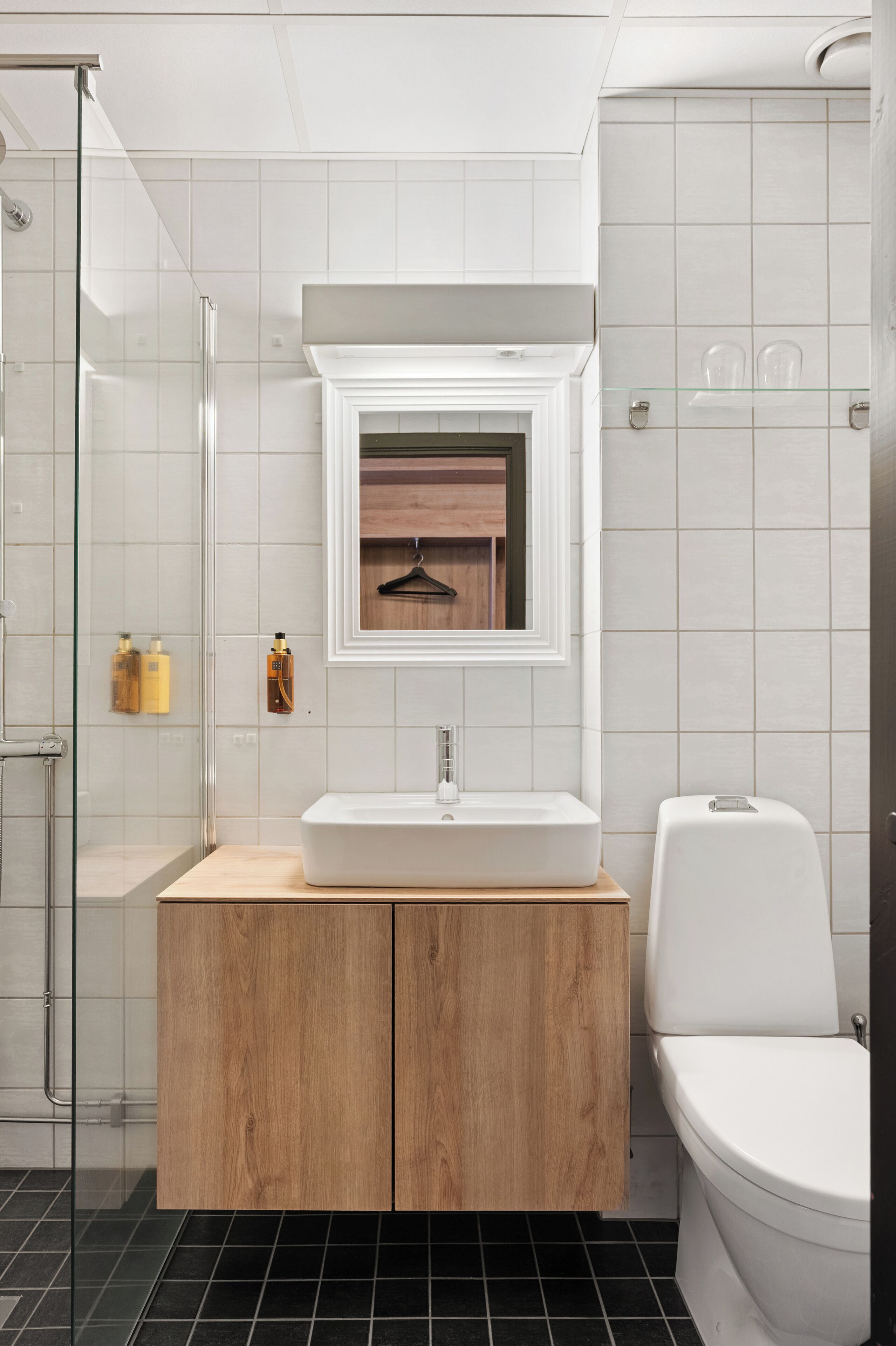 Une salle de bain moderne avec une douche à parois de verre, un meuble-lavabo en bois et des toilettes.