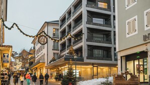 Monikerroksinen hotelli, jossa on parvekkeet, lumipeitteinen maa ja joulukoristeet.
