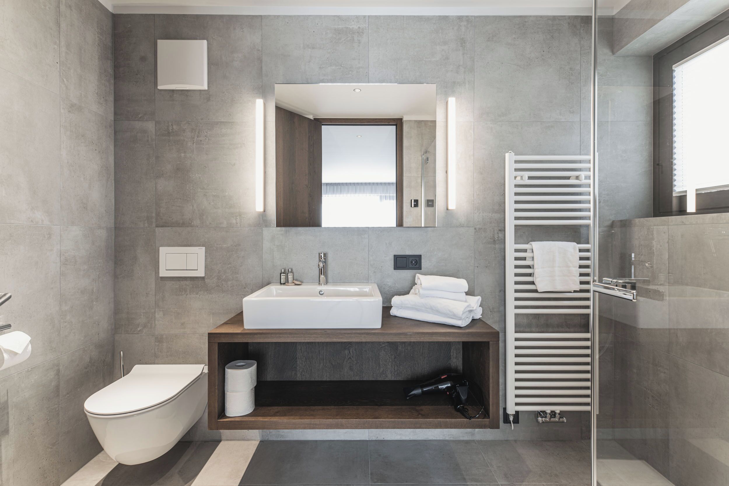 Ein modernes Badezimmer mit einem großen Waschbecken, einer Toilette und einer begehbaren Dusche.