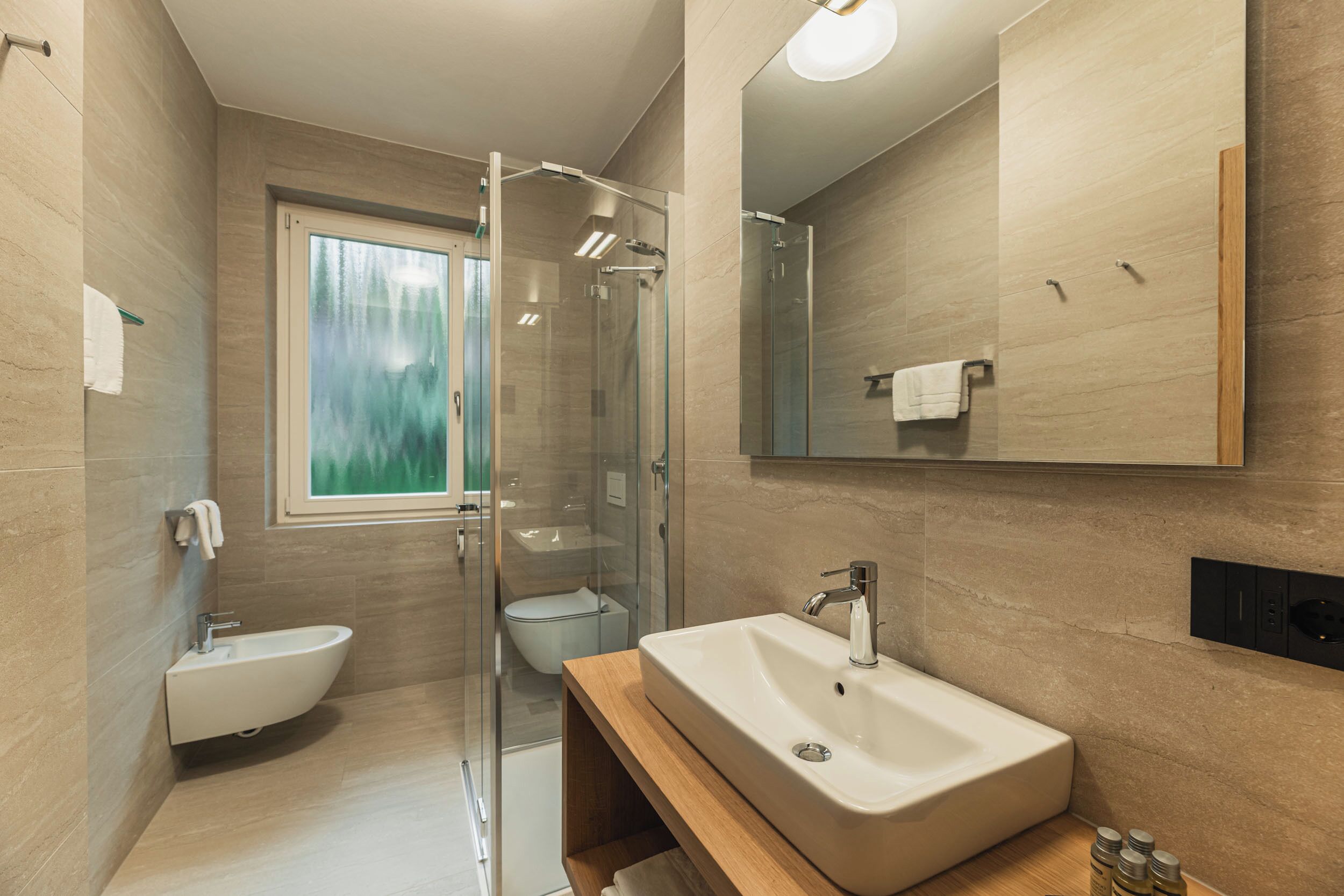 A modern bathroom with a glass-enclosed shower, a standalone sink, and a toilet.