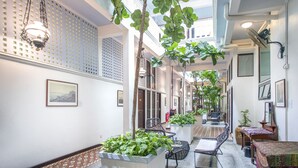 A hotel corridor with hanging plants, wicker furniture, and framed pictures on the walls. - Areca Hotel Penang (George Town)
