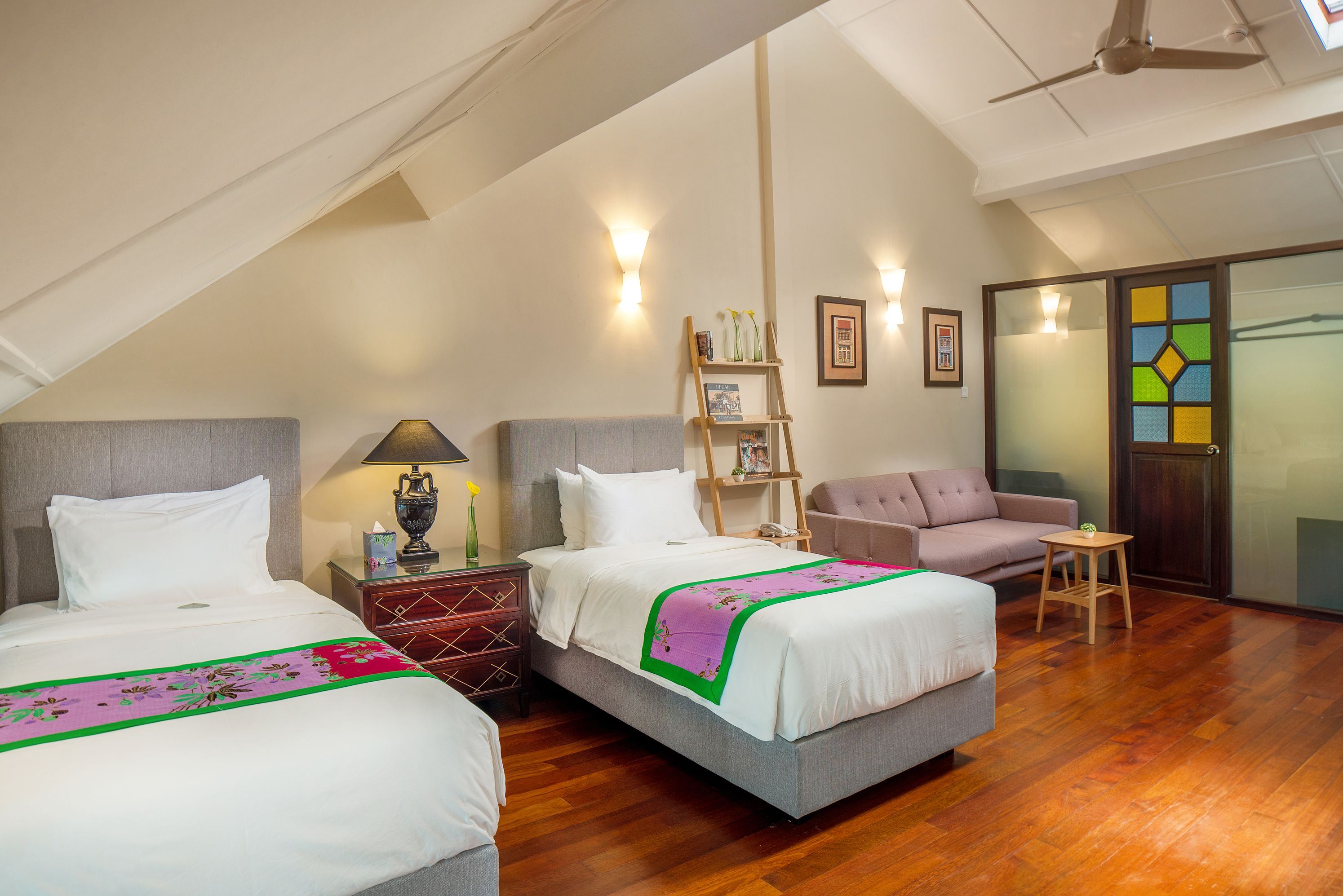 A hotel room with two beds, a sofa, a small table, and a ladder.