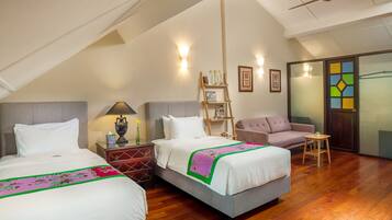 A hotel room with two beds, a sofa, a small table, and a ladder.