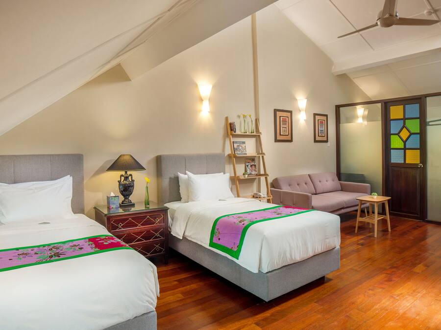 A hotel room with two beds, a sofa, a small table, and a ladder.