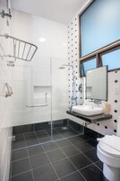 Ein modernes Badezimmer mit Duschkabine aus Glas, einem weißen Waschbecken und einem großen Spiegel.