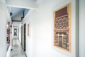 Un pasillo con suelo de baldosas, paredes blancas y un dibujo arquitectónico enmarcado a la derecha.