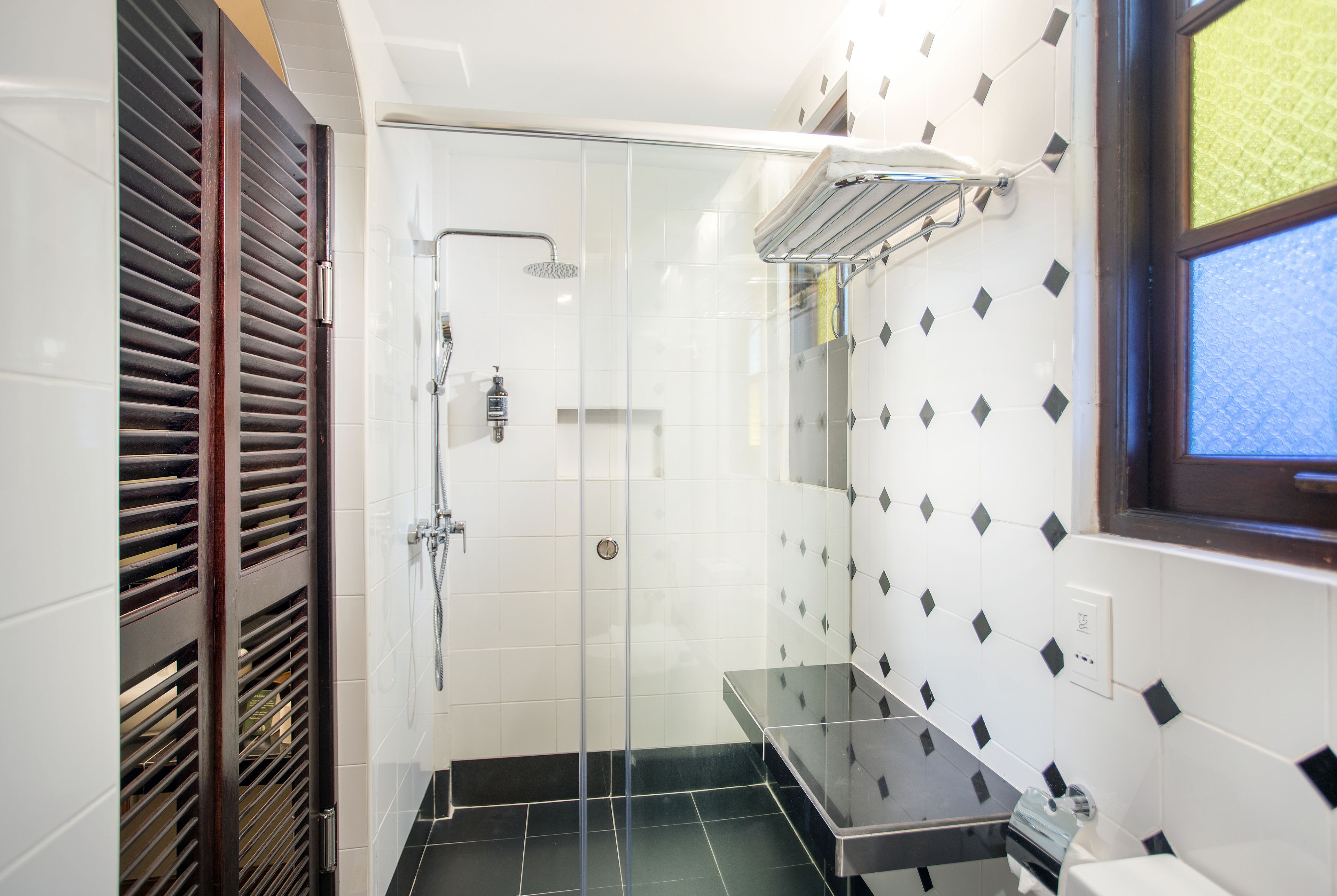 A modern bathroom with a glass-enclosed shower, a black countertop, and a window with a view.