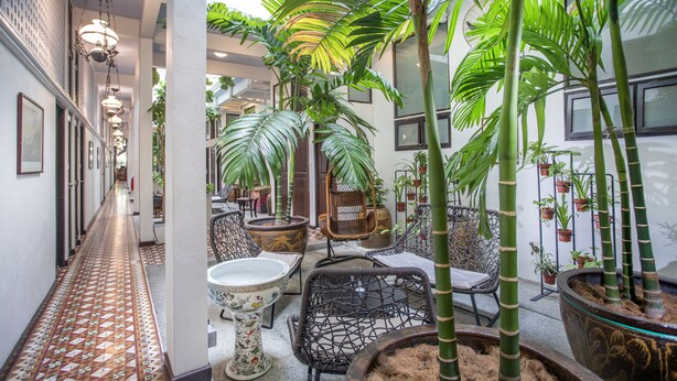A hallway with a tiled floor, wicker furniture, and potted plants. - Areca Hotel Penang (George Town)