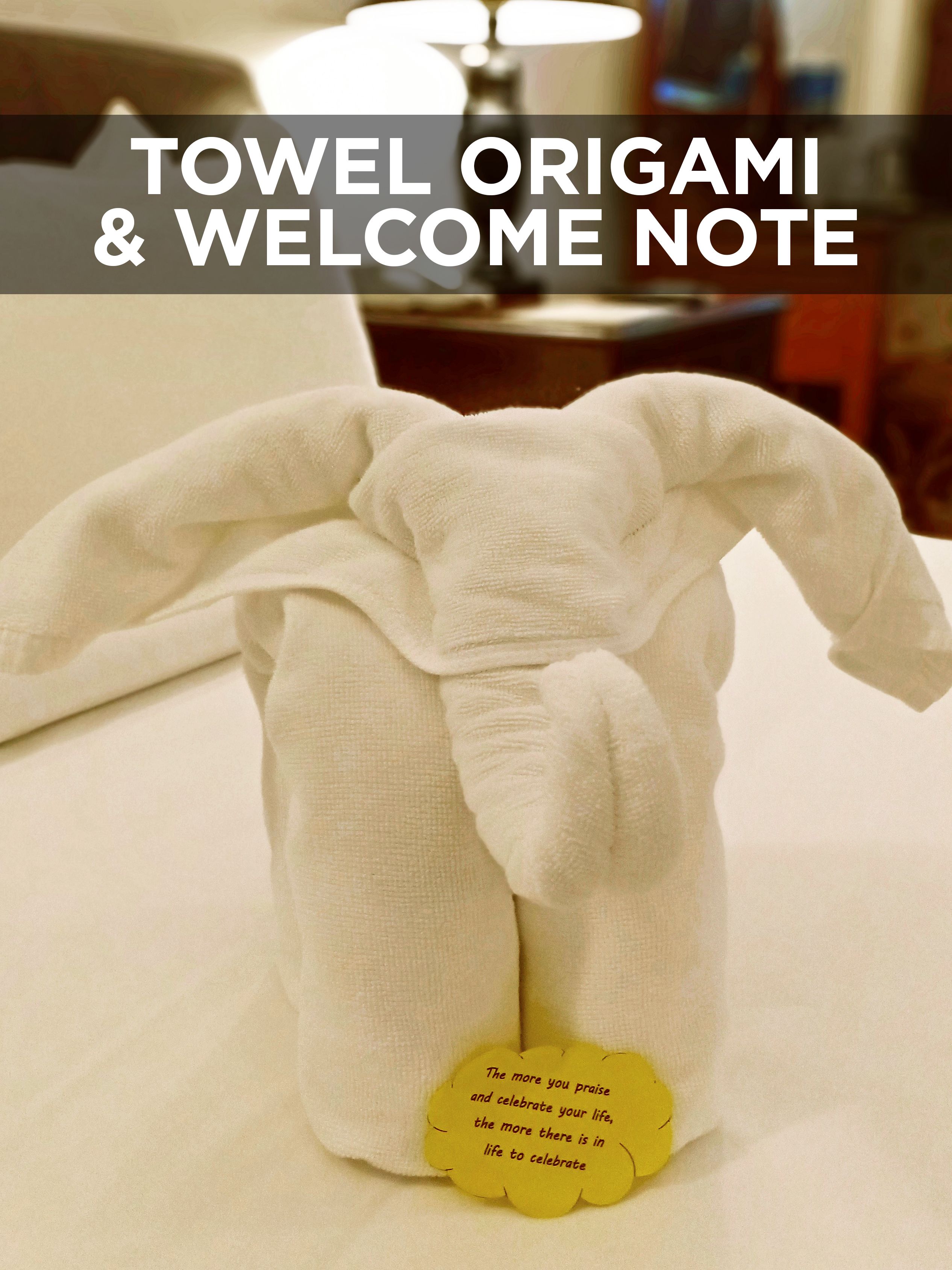 A towel origami and welcome note on a bed.