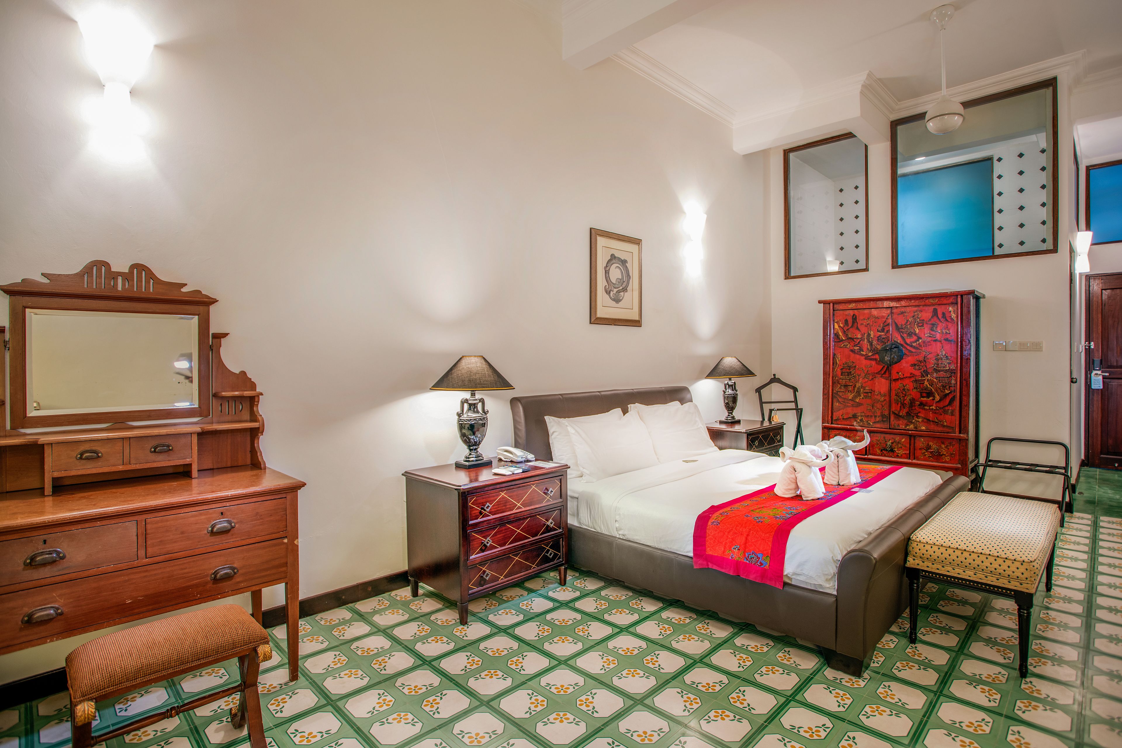 A hotel room with a bed, a dresser, a nightstand, a chair, and a mirror.