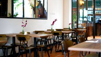 Un interior de restaurante con varias mesas y sillas, algunas decoradas con flores.
