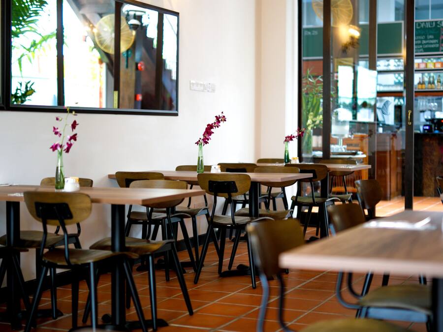 Un interior de restaurante con varias mesas y sillas, algunas decoradas con flores.