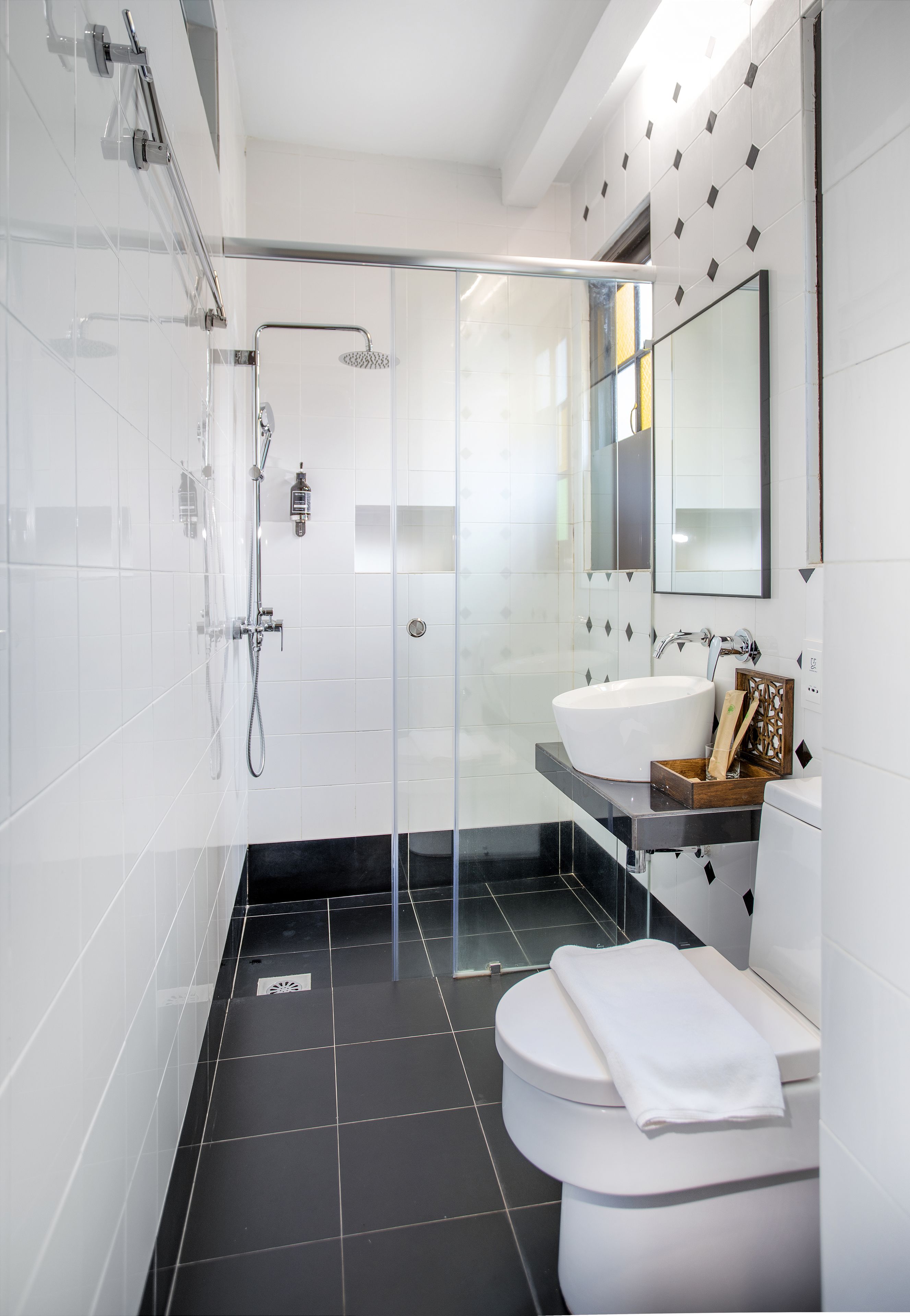 A modern bathroom with a glass-enclosed shower, a white sink, and a toilet.