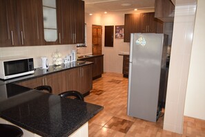 A kitchen with wooden cabinets, a stainless steel refrigerator, a microwave, and a coffee maker.