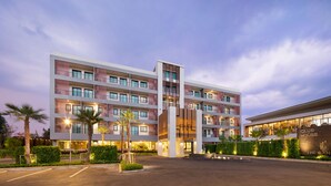 A multi-story hotel with a modern design, featuring balconies, a landscaped courtyard, and a well-lit entrance. - The Canal 304 (Si Maha Phot)