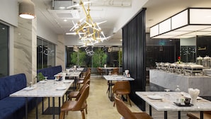 A modern restaurant interior with marble flooring, wooden chairs, and a central dining area with a long table. - The Canal 304 (Si Maha Phot)