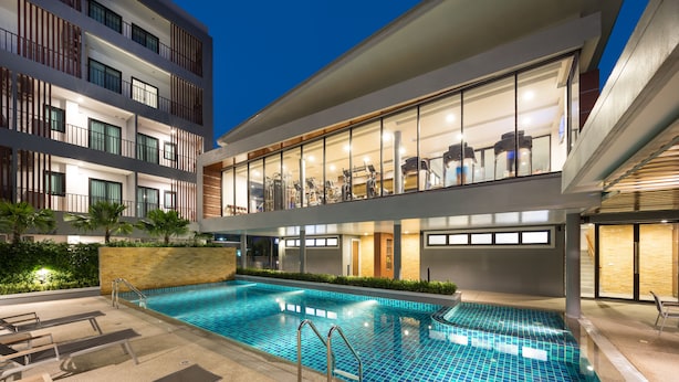 A modern hotel with a swimming pool, outdoor seating, and a fitness center visible through large windows. - The Canal 304 (Si Maha Phot)