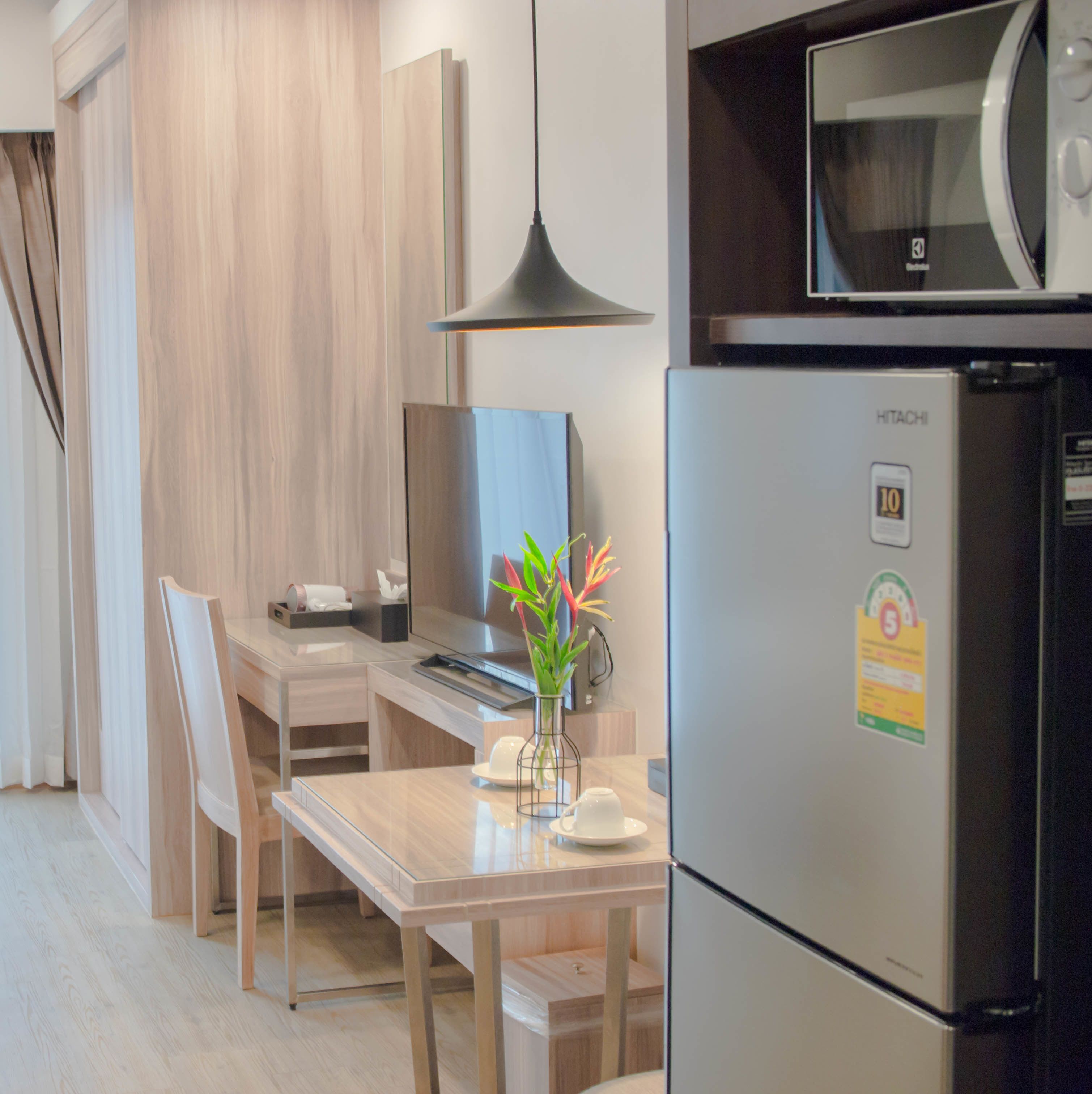 Eine moderne Küche mit integriertem Mikrowellenherd, einem Edelstahlkühlschrank und einem Essbereich mit Holztisch und Stühlen.