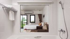 A modern bathroom with a bathtub, a shower, and a large window. - The Canal 304 (Si Maha Phot)