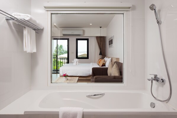 Un baño moderno con bañera, ducha y un amplio ventanal.