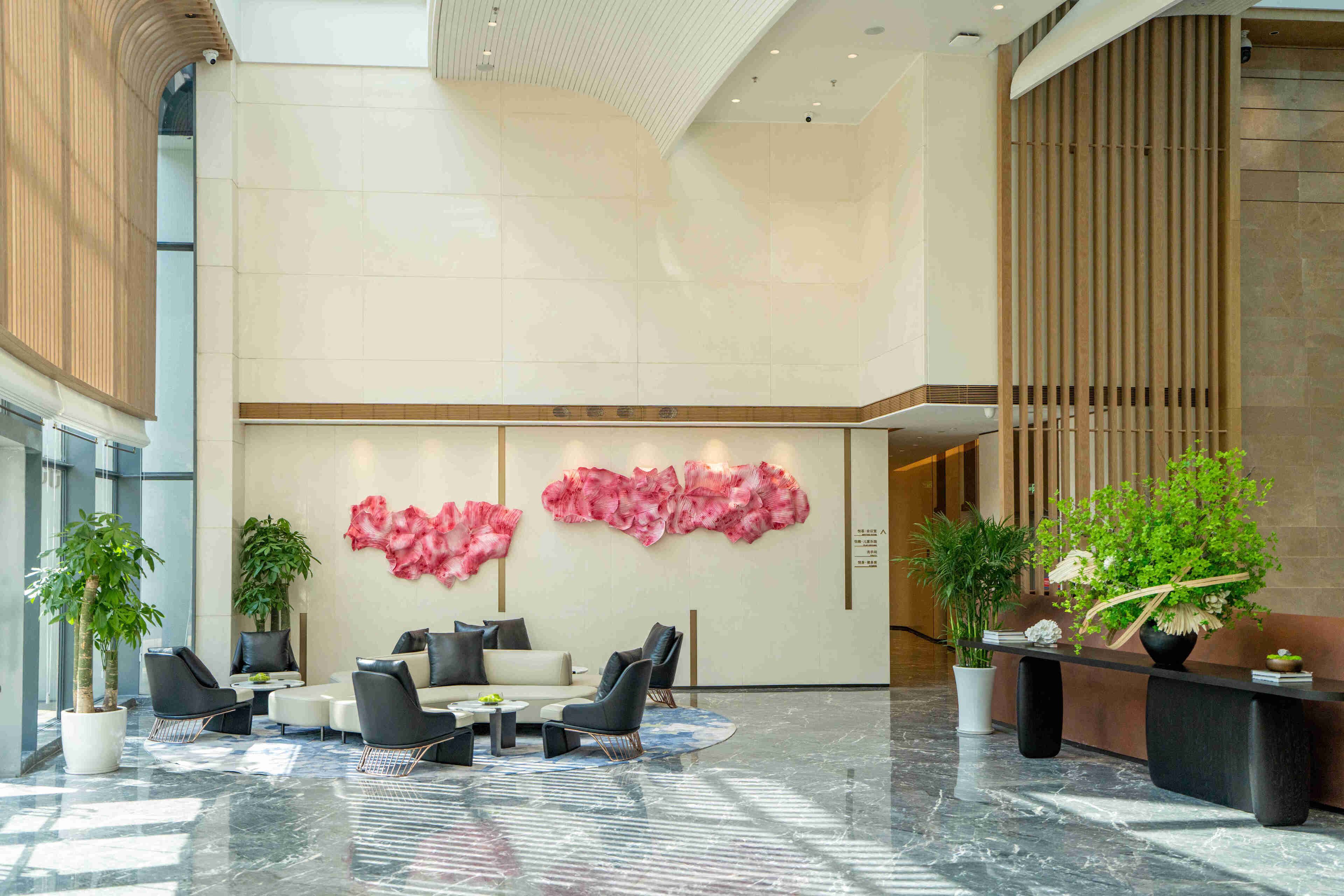 A modern lobby with a seating area, large windows, and decorative plants.