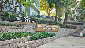 A stone wall with a sign for CM+ Serviced Apartment Shenzhen Taige.