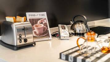 A kitchen counter with a toaster, a kettle, a teapot, a coffee pod, and a magazine titled "FOOD AND TIME".